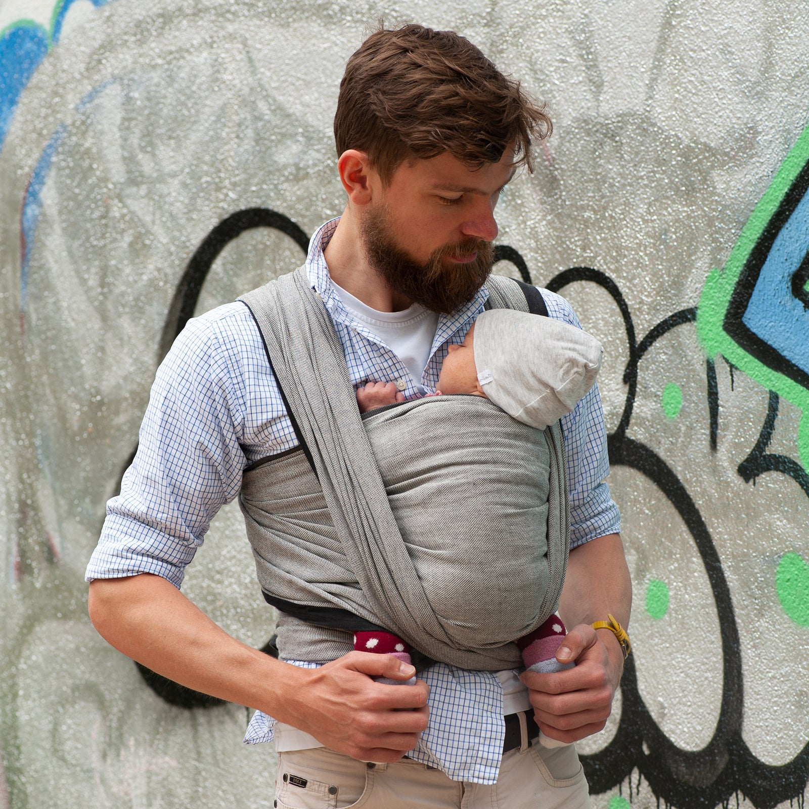 Tragetuch Tulum gebunden von Papa mit süßem Baby vor einer Wand mit Graffiti
